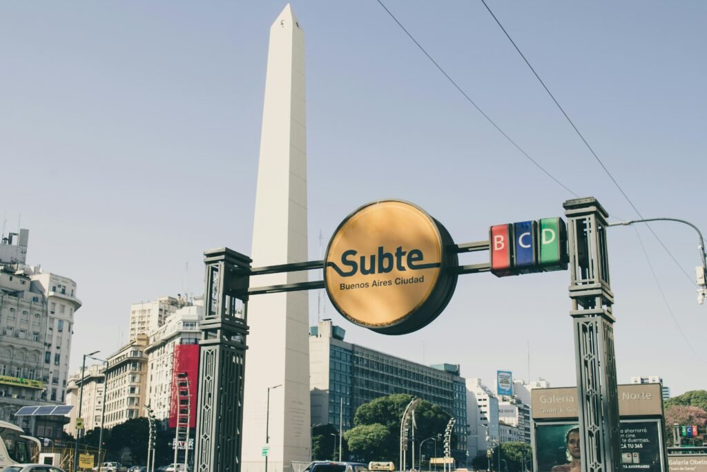 View of the Obelisk in Buenos Aires with prominent Subte signage against a clear sky.